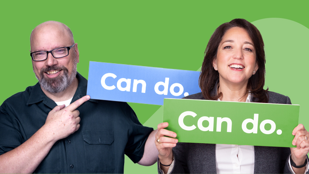 Two smiling Smartsheet customers hold signs that read “can-do.”